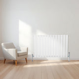 Platt enkelpelarradiator i vitt, 600 x 910 mm, placerad på en ljus trägolv med en modern fåtölj i bakgrunden