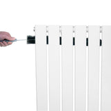 Vit platt enkelpelarradiator i 600 x 910 mm med en hand som rengör radiatorns ribbor med en borste