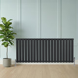 Platt enkelpelarradiator i antracitgrå, 600 x 1400 mm, med släta ytor och vertikala lameller, placerad framför en vägg och en krukväxt