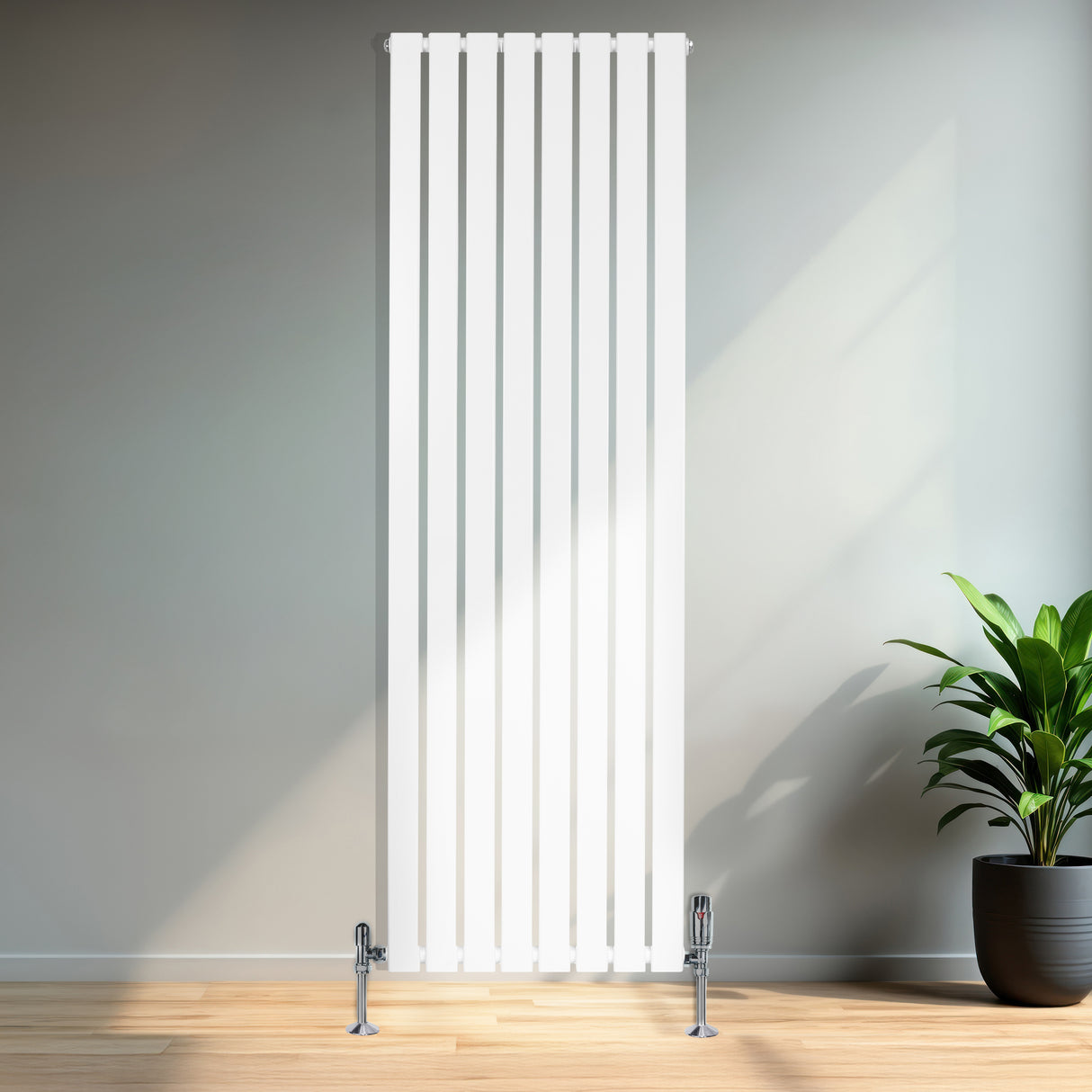 Hög, platt enkelpelarradiator i vit färg med släta ytor och vertikala ribbor, placerad mot en ljus vägg i ett modernt rum