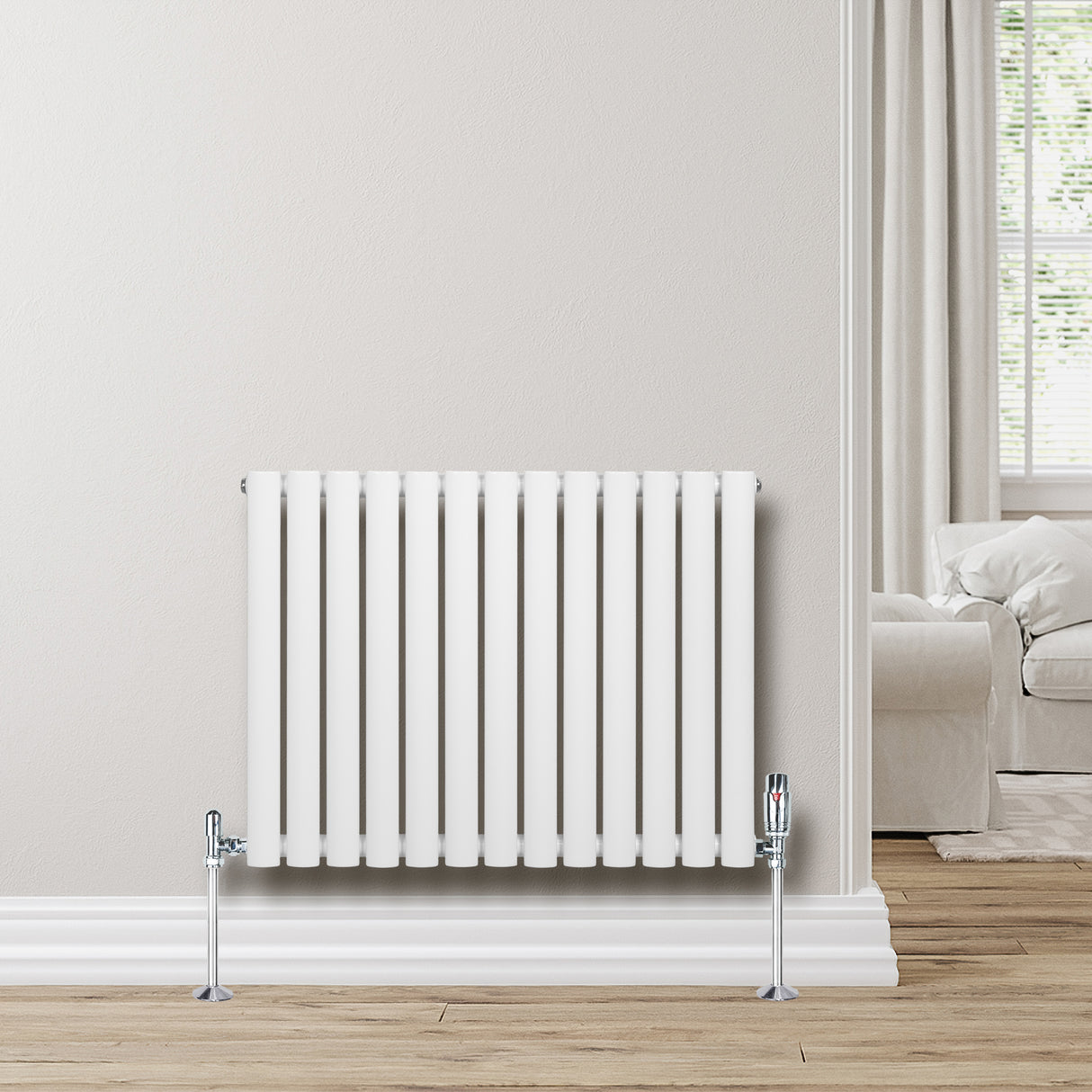 Oval enkelpelarradiator i vit färg, 600 x 780 mm, med släta ytor och kromade fästen, placerad mot en ljus vägg i ett rum