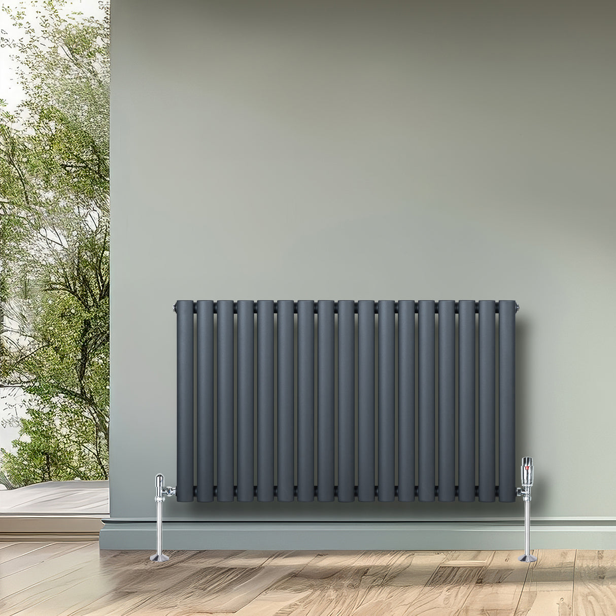 Oval enkelpelarradiator i antracitgrå, 600 x 1020 mm, med släta, vertikala ribbor och glänsande kromade ventiler, placerad mot en ljusgrön vägg