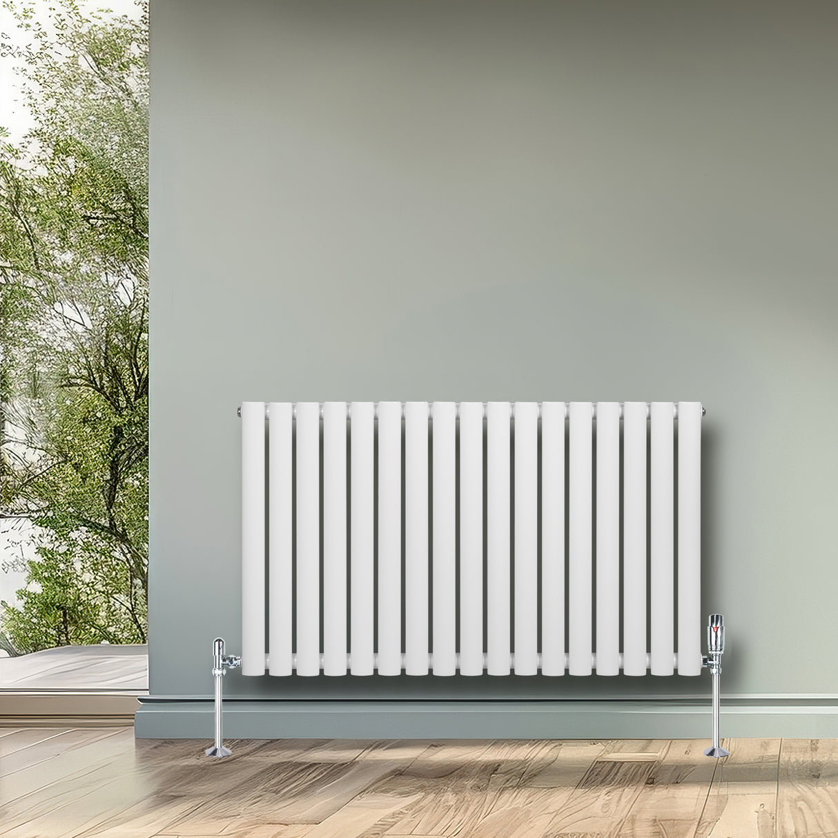 Oval vit enkelpelarradiator med släta, vertikala ribbor och kromade fötter, placerad mot en grön vägg i ett ljust rum