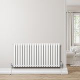 Oval enkelpelarradiator i vit färg, 600 x 1200 mm, med släta ytor och kromade ventiler, placerad mot en ljus vägg i ett modernt rum