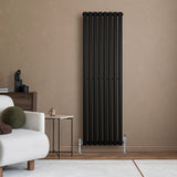Oval svart enkelpelarradiator, 1600 x 480 mm, med släta ytor och moderna linjer, placerad på en beige vägg i ett stilrent rum