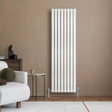 Oval vit enkelpelarradiator med släta, glänsande ytor och sju vertikala sektioner, placerad mot en varm beige vägg