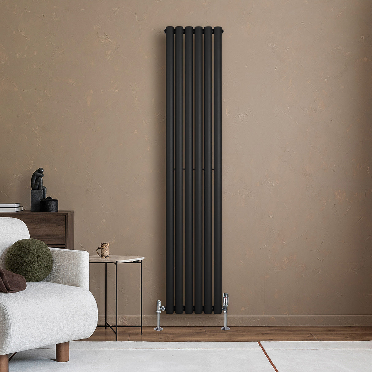 Oval enkelpelarradiator i svart, 1800 x 360 mm, med släta ytor och moderna linjer, placerad mot en beige vägg i ett stilrent rum