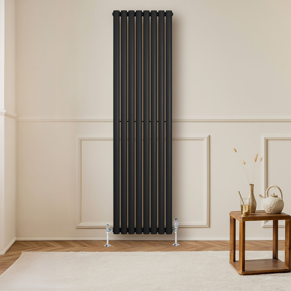 Svart oval enkelpelarradiator i metall, 1800 x 480 mm, monterad på vägg i ett rum med ljusa väggar och trädetaljer