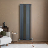 Oval enkelpelarradiator i antracitgrå, 1800 x 600 mm, med släta ytor och moderna linjer, placerad mot en beige vägg