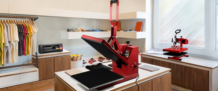 Röd värmepressmaskin på ett modernt arbetsbord med kläder och tillbehör i en ljus och luftig butiksmiljö